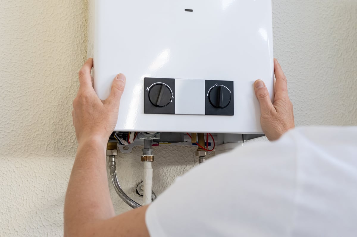 Plumber's hands adjusting gas water heater